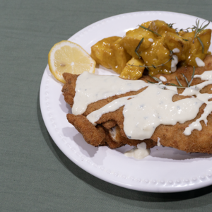 Milanesa de merluza con salsa suave de queso azul y papas a la mostaza